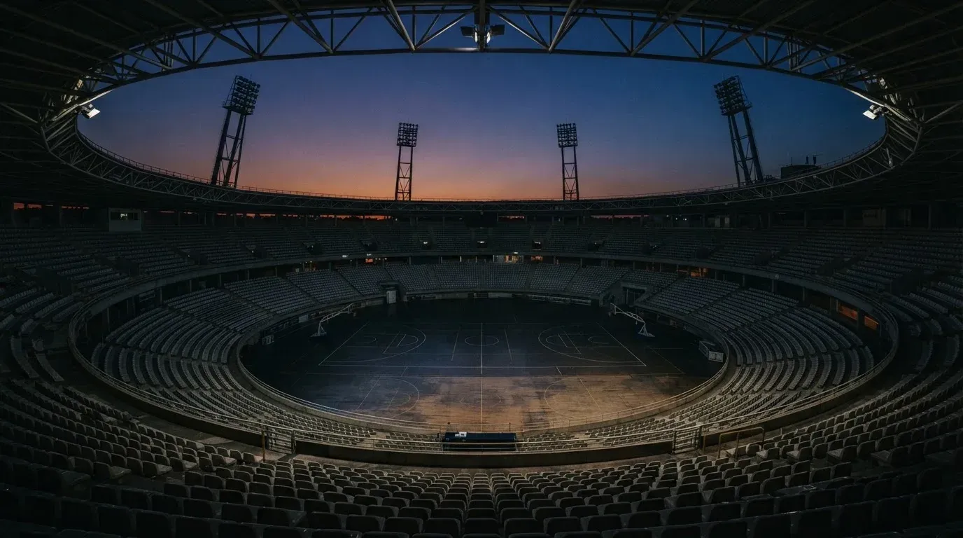 An empty football stadium with floodlight masts at dusk