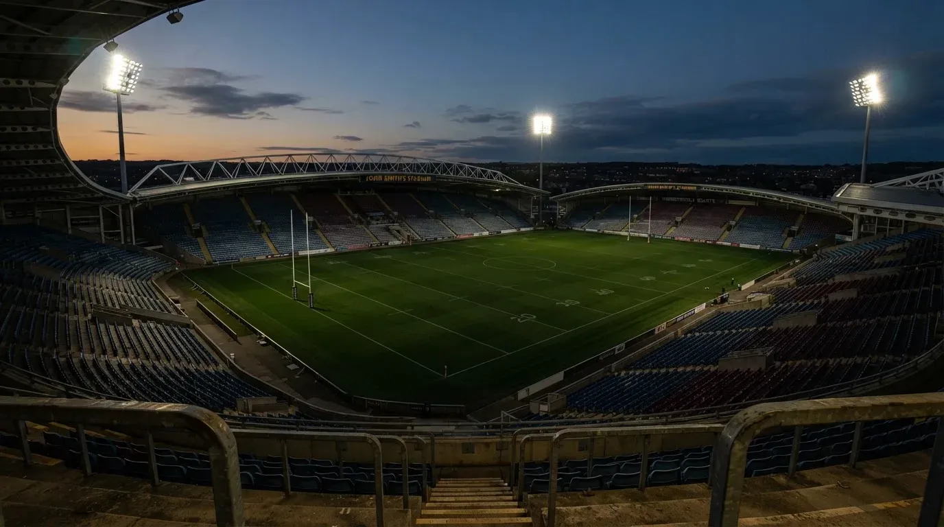 An empty football stadium with floodlight masts at dusk