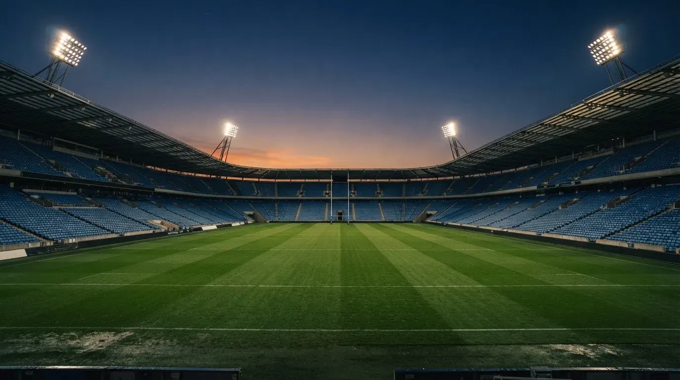 An empty football stadium with floodlight masts at dusk