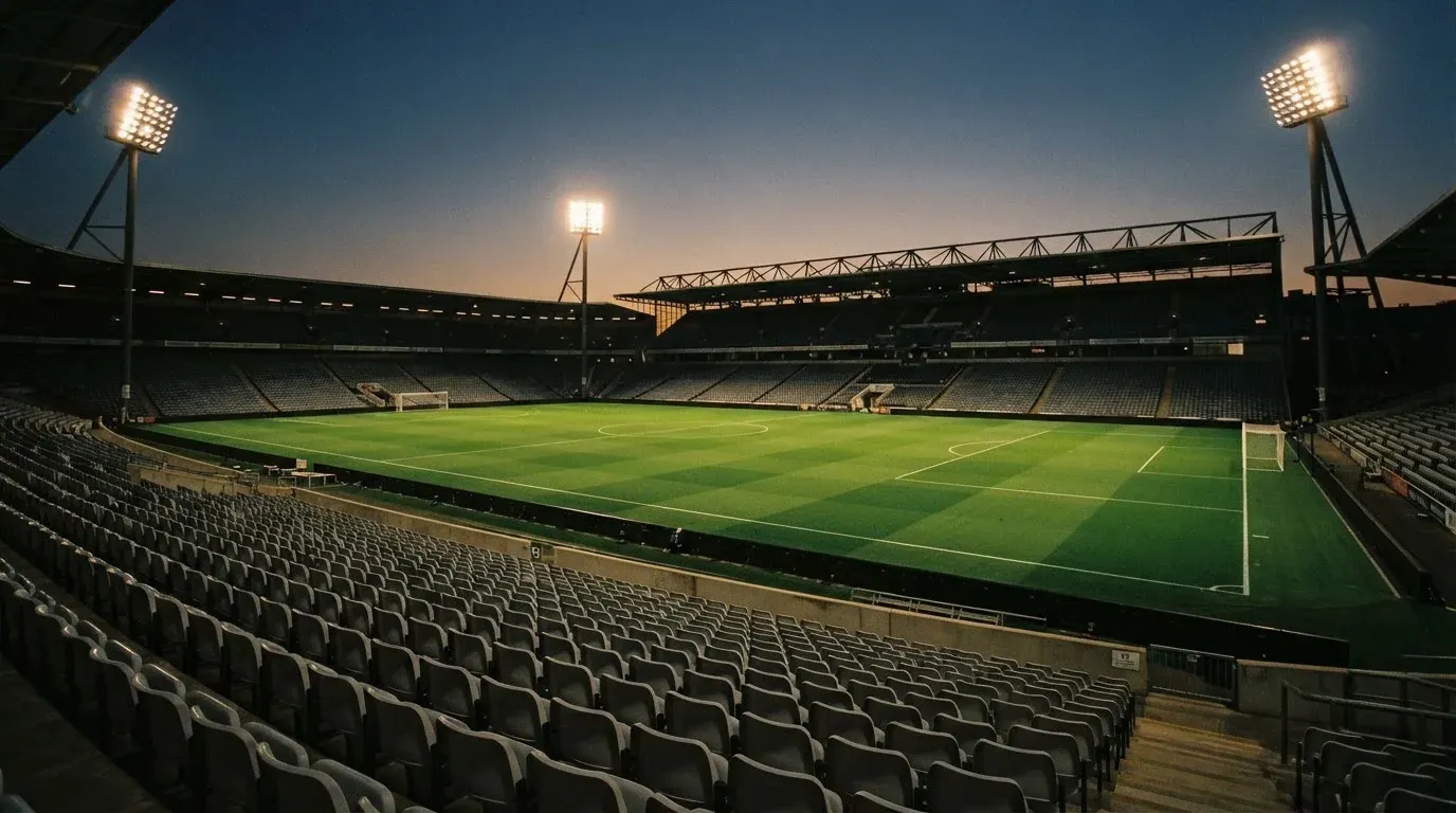 An empty football stadium with floodlight masts at dusk