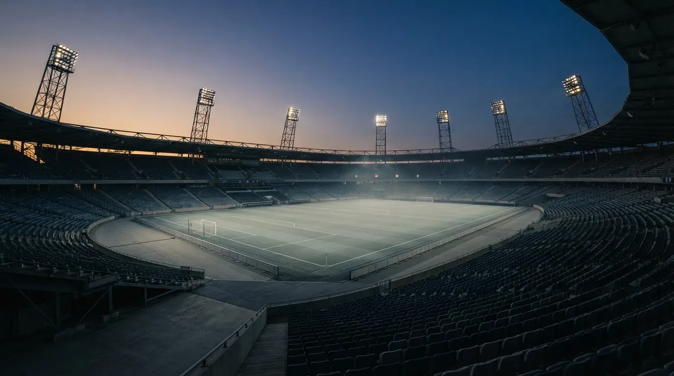 An empty football stadium with floodlight masts at dusk