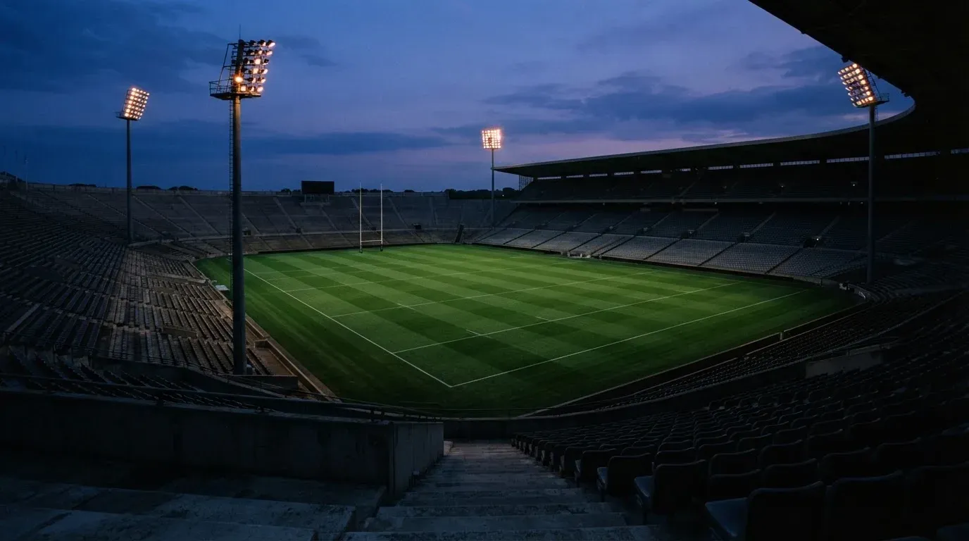An empty football stadium with floodlight masts at dusk