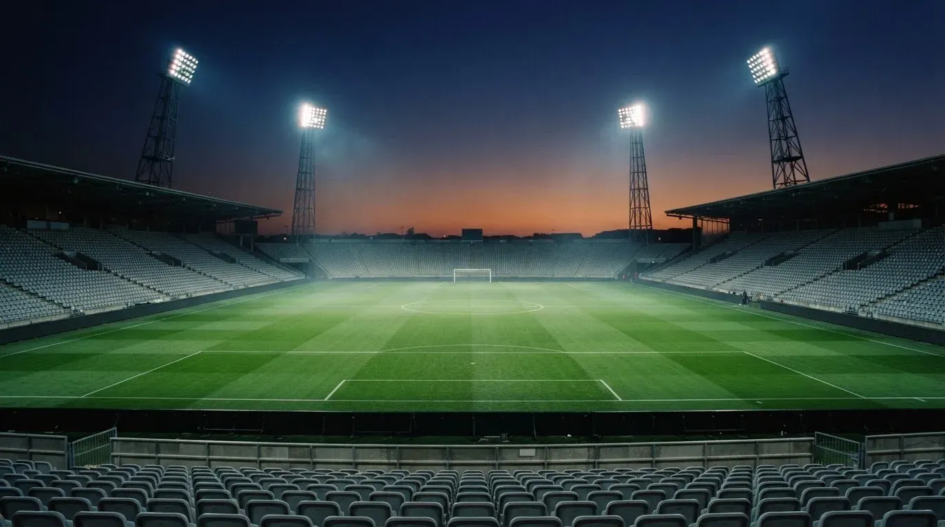 An empty football stadium with floodlight masts at dusk