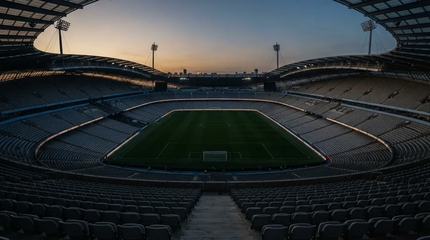 An empty football stadium with floodlight masts at dusk