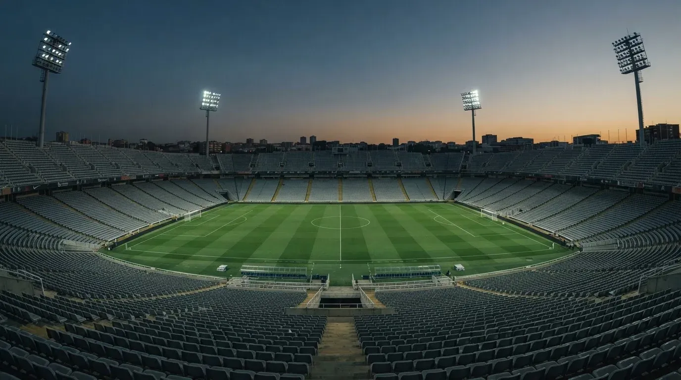 An empty football stadium with floodlight masts at dusk