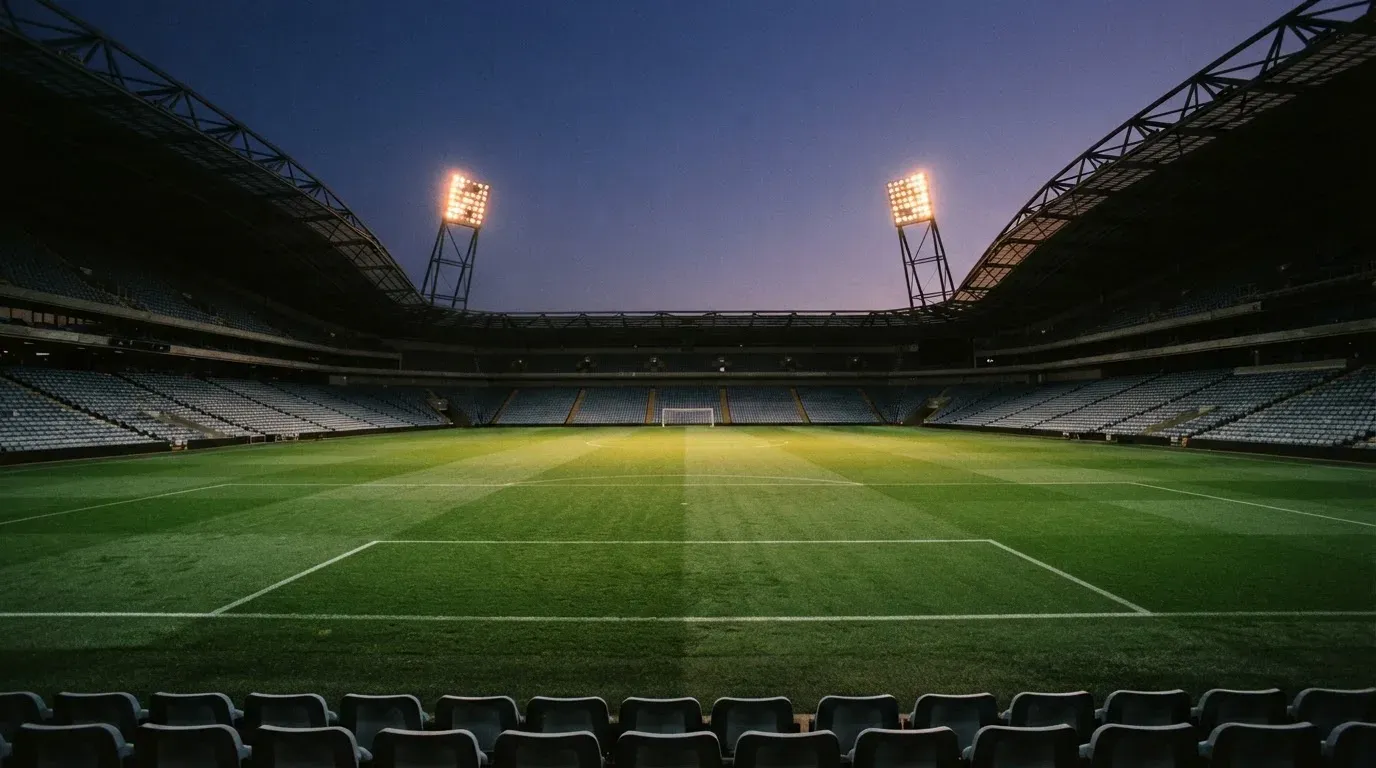 An empty football stadium with floodlight masts at dusk