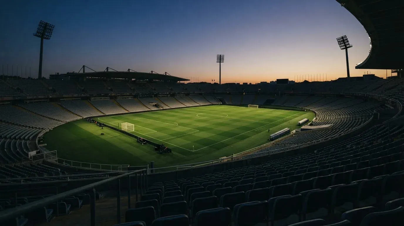 An empty football stadium with floodlight masts at dusk