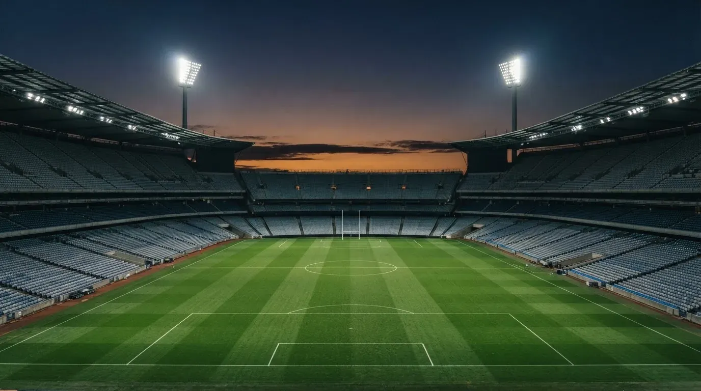 An empty football stadium with floodlight masts at dusk