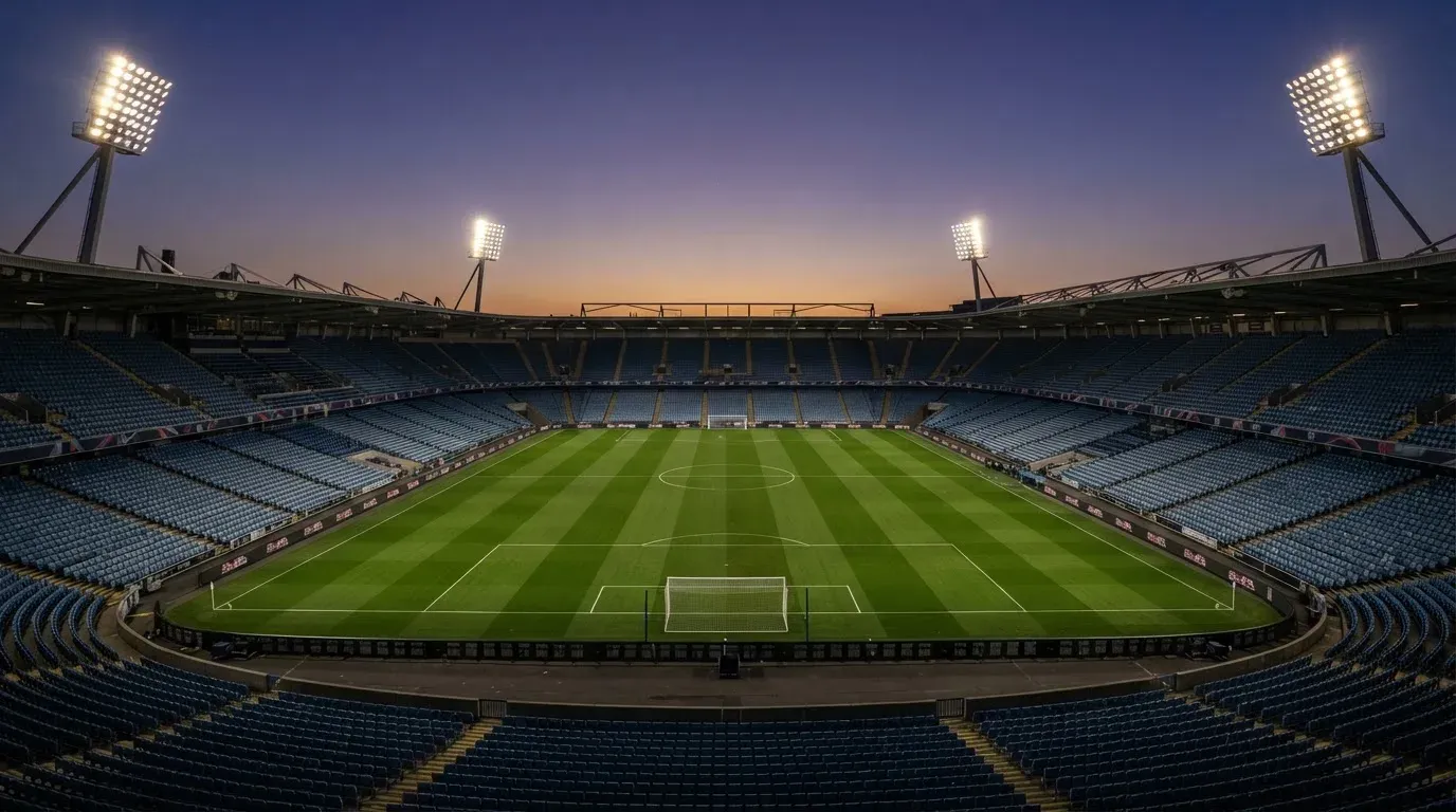 An empty football stadium with floodlight masts at dusk