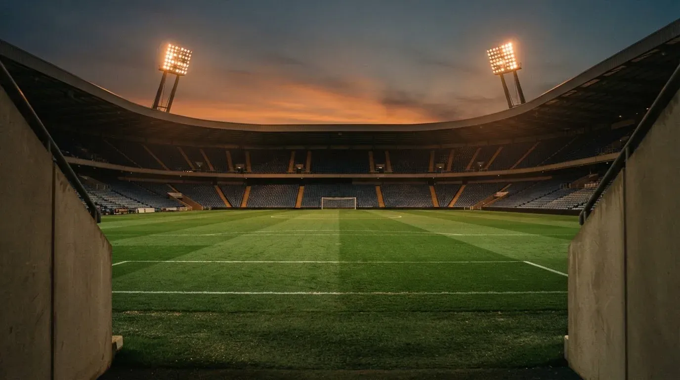 An empty football stadium with floodlight masts at dusk
