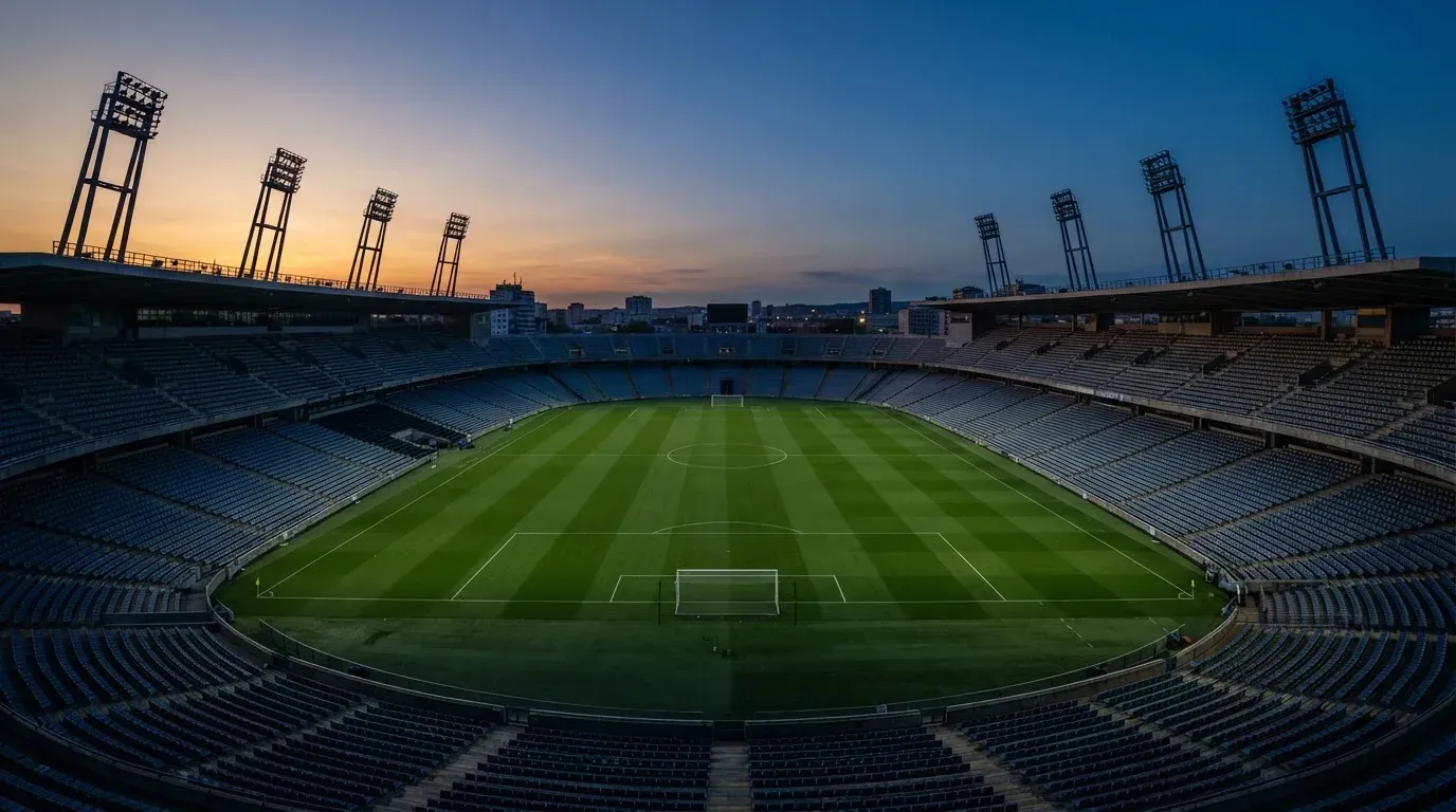 An empty football stadium with floodlight masts at dusk
